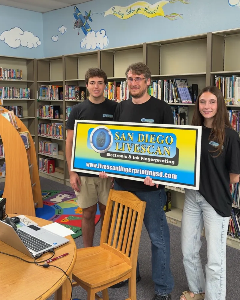 The San Diego Livescan mobile team holding the company sign at a school event